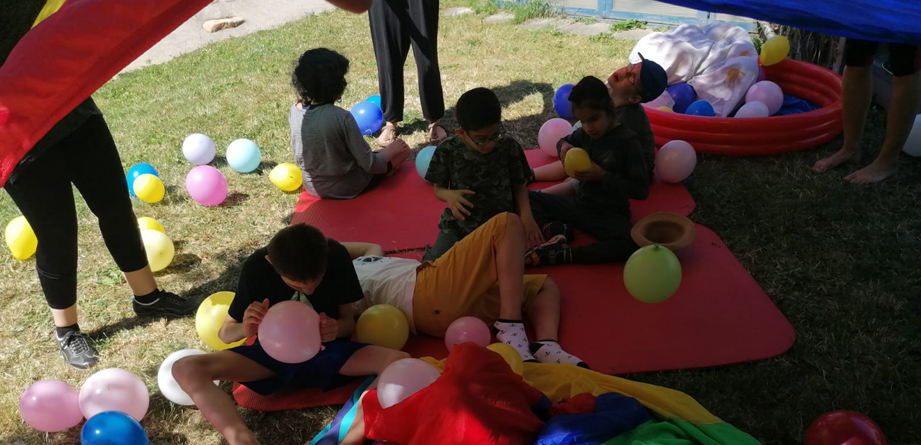 Kinder mit Luftballons sitzen im Gras