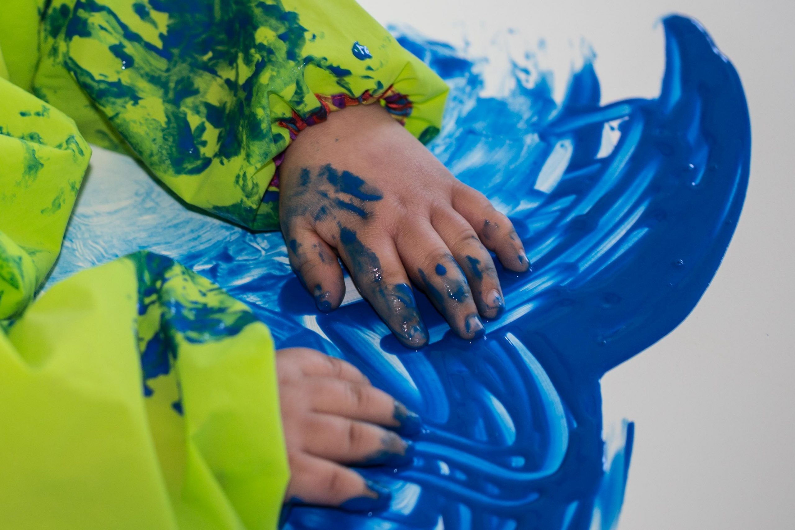 Kinderhände, die mit blauer Farbe malen