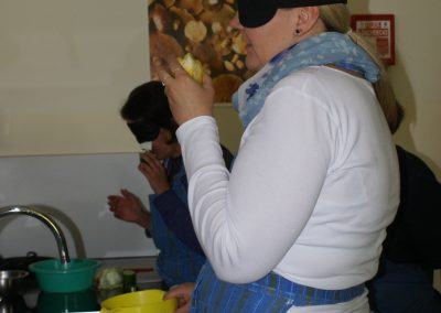 Workshop 10 von Fr. Löbl und Fr. Daniel. Eine Teilnehmerin, welche eine Simulationsbrille für Blindheit trägt, erlebt Kochen mit all ihren restlichen Sinnen.
